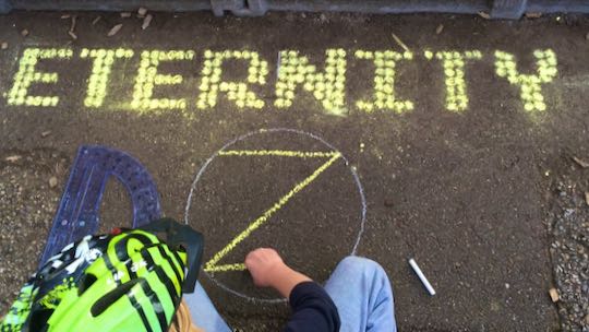 Example: Eternity written in chalk DOTS. Child drawing dotZero in foreground.