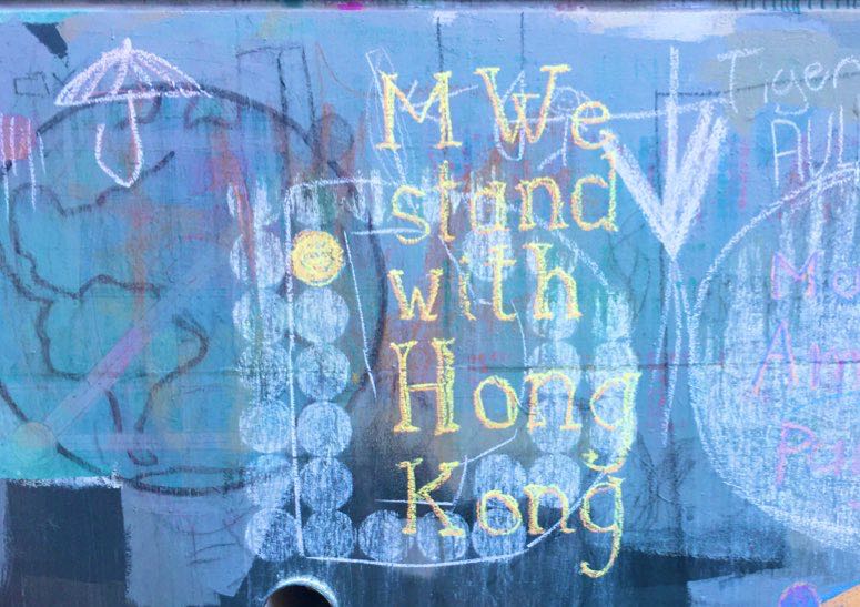 Example: 'MWe Stand with Hong Kong' in chalk, with umbrella