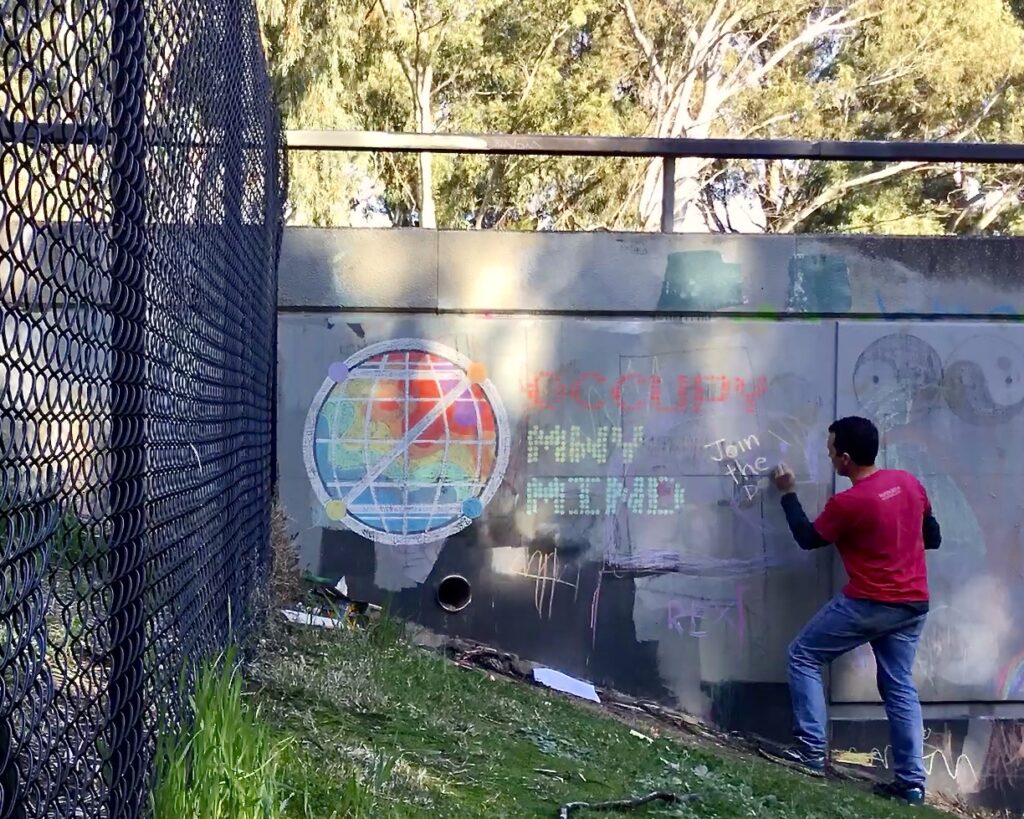 Chalk Wall: Man chalking 'Occupy MWy Mind'